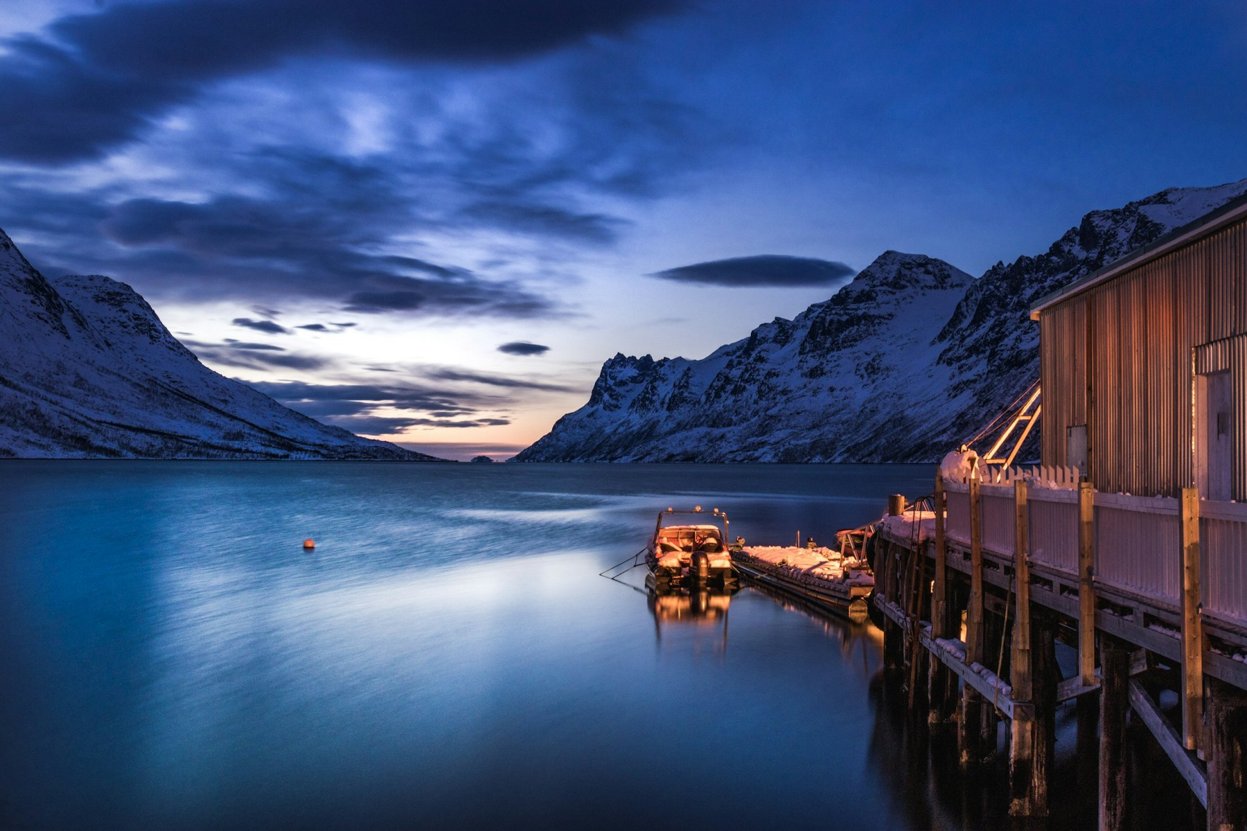 Boat moored beside northern houses beneath an aurora-lit sky